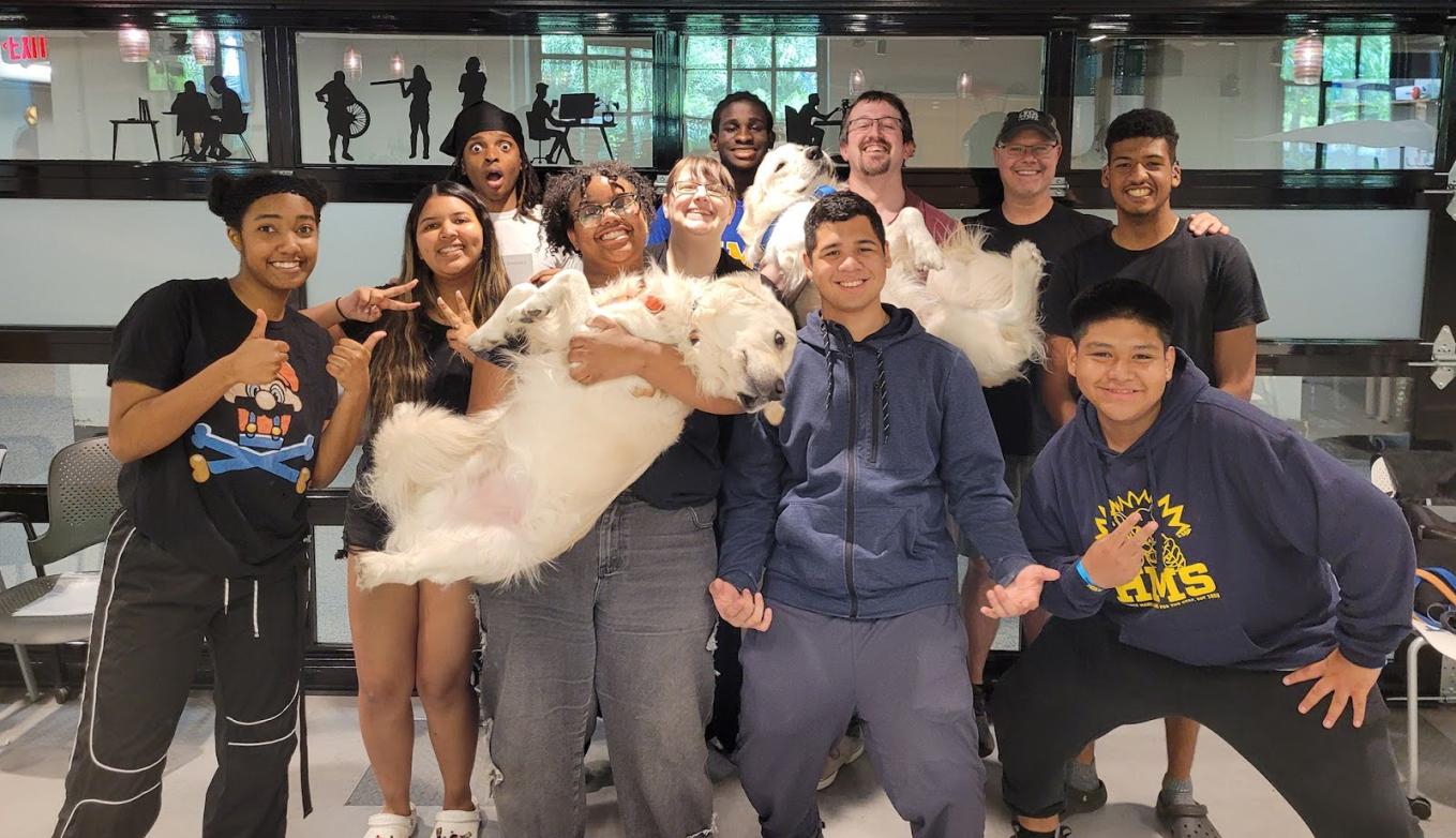 a group of students and instructors smiling for the camera, two holding large white dogs