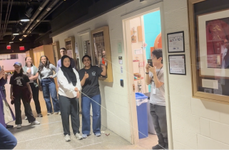 A group of students gathers at one end of Strobe Alley ready to watch an egg travel a pulley system down the hallway.