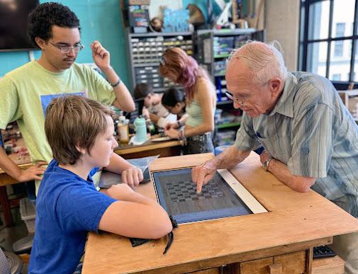 Edgerton Center Director Prof. Kim Vandiver plays touch-screen checkers with an EDW participant on the project created by "Knights of the Game Table"